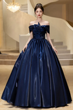 Woman in a navy blue evening gown standing in an elegant interior setting.