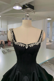 Black evening gown with silver embellishments on a mannequin in an indoor setting.