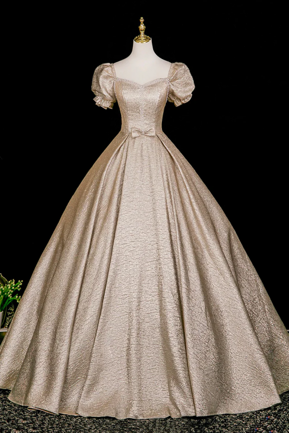 Beige vintage-style gown on a mannequin against a black background