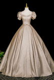 Beige vintage-style gown on a mannequin against a black background