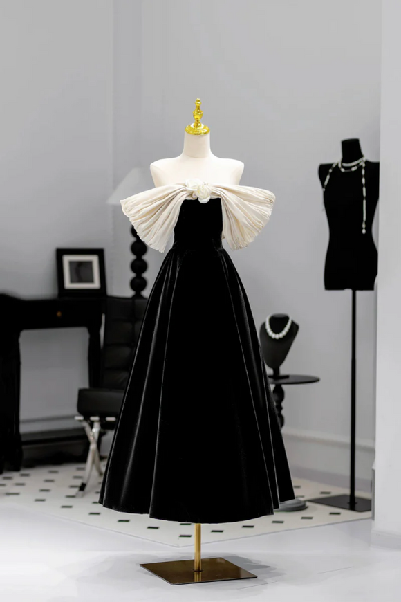 Black evening gown with white bow on a mannequin against a gray wall.