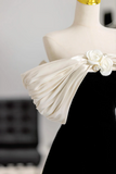 Mannequin wearing a black dress with a white floral detail on a blurred background