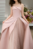 Pink strapless gown with a layered skirt in a blurred indoor setting