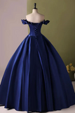 Navy blue evening gown on a mannequin against a green wall.