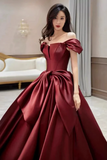 Woman wearing a burgundy off-shoulder gown in an elegant room.