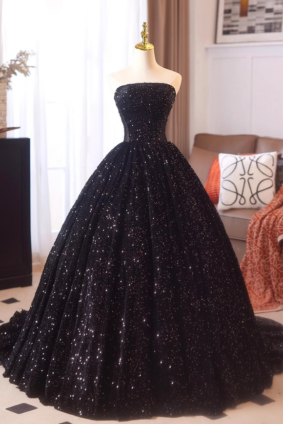 Black sequin gown on a mannequin in a room with a couch and decorative pillows.