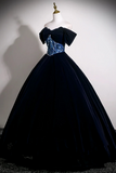 Black evening gown with blue sequin details on a mannequin against a plain background