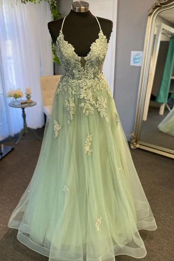Light green evening gown with floral lace details on a mannequin in a room.