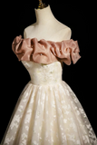 White lace dress with pink ruffled top on a mannequin against a black background