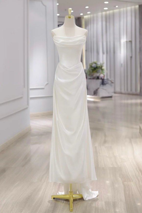 White strapless evening gown on a mannequin in a showroom setting.