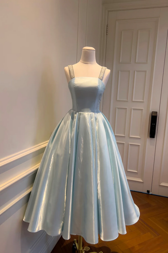 Light blue dress on a mannequin against a white door.