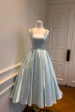 Light blue dress on a mannequin against a white door.