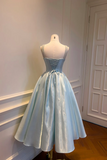 Light blue evening gown on a mannequin against a white wall.
