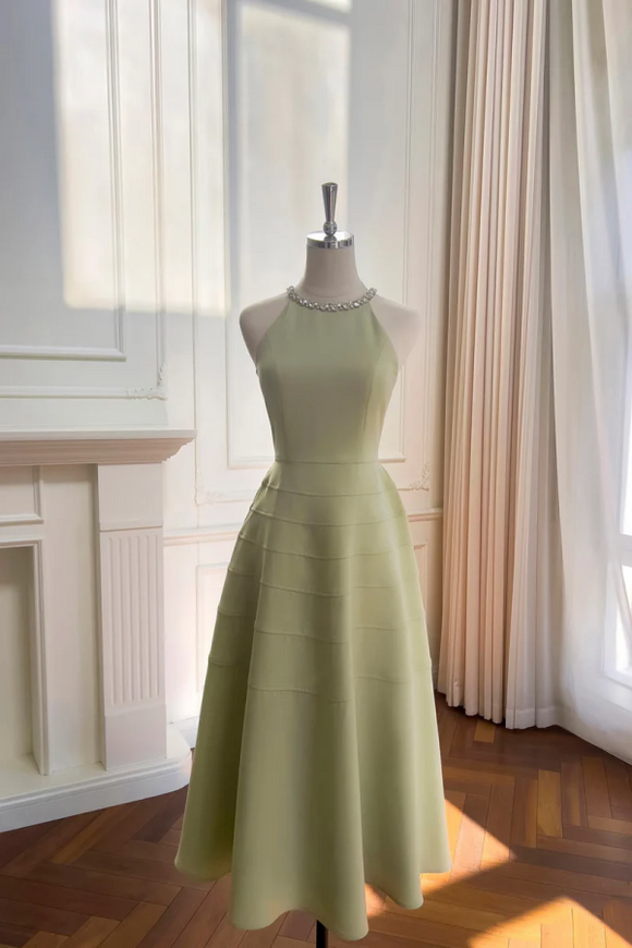 Light green dress on a mannequin in a room with curtains and a fireplace.