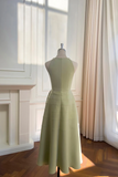 Light green dress on a mannequin in a room with a fireplace and curtains.