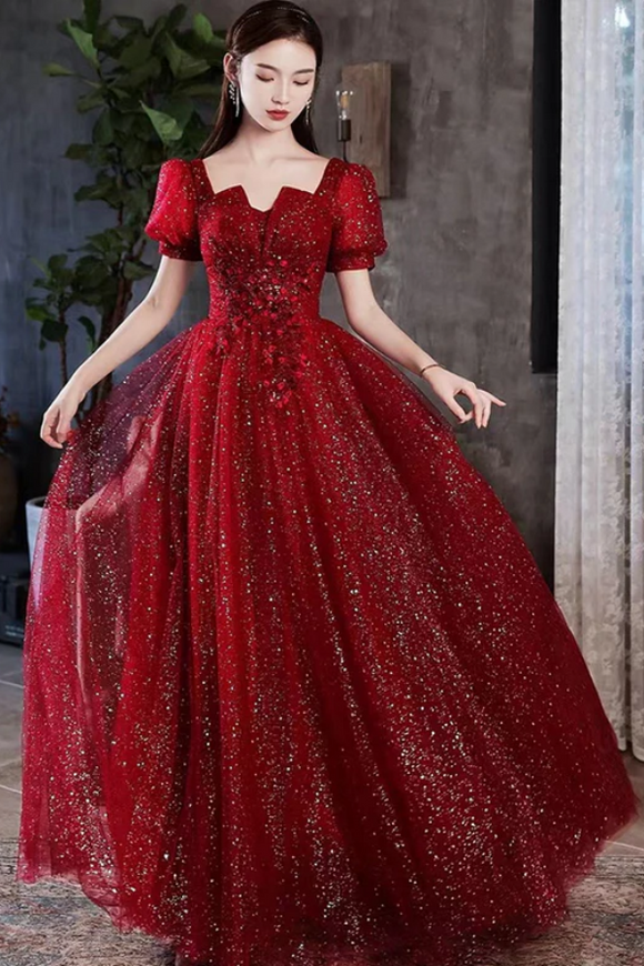 Woman wearing a red sparkly dress indoors with a neutral background