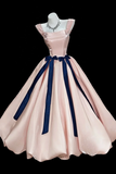 Pink evening gown with navy blue ribbons on a mannequin against a black background