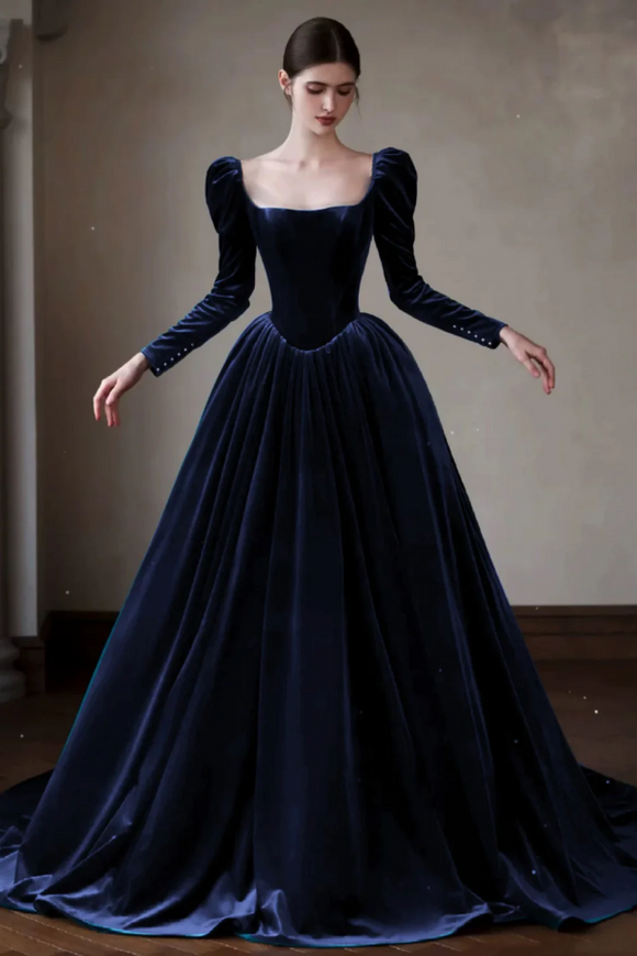 Woman wearing a long, dark blue velvet gown with puffed sleeves against a plain background.
