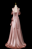 Pink satin gown on a mannequin against a black background