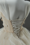 Close-up of a beige corseted dress on a mannequin against a dark background