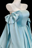 Light blue evening gown with a large bow on a mannequin against a black background