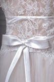 Close-up of a lace dress with a white satin ribbon bow