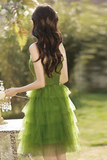 Woman in a green dress standing outdoors with a blurred natural background