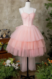 Pink tiered dress on a mannequin against a rustic wall with plants.