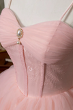 Close-up of a pink dress with a decorative bow and pearl detail.