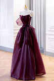 Burgundy evening gown on a mannequin against a white curtain background