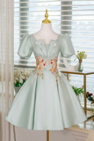 Light green dress with floral embroidery on a mannequin against a blurred indoor background
