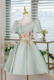 Light green dress with floral embroidery on a mannequin against a window background.