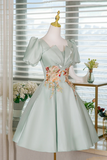 Light green dress with floral embroidery on a mannequin against a blurred indoor background