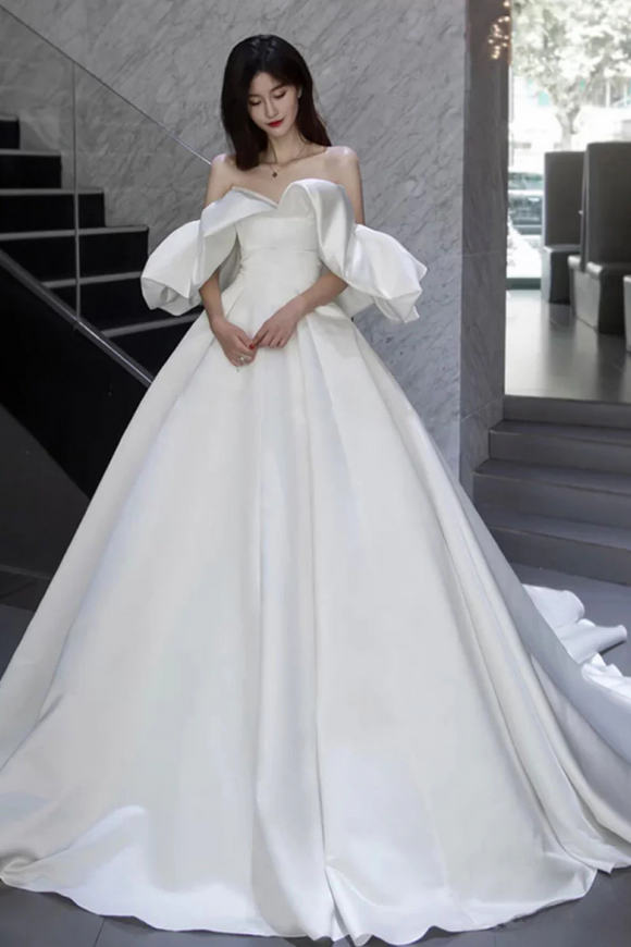 Woman in a white wedding dress standing in an indoor setting.