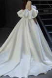 White off-shoulder gown with ruffled details on a dark background