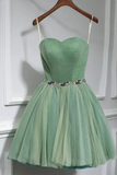 Green dress with a floral belt on a hanger against a white wall