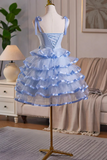 Blue tiered dress on a mannequin in a room setting with a lamp and sofa.