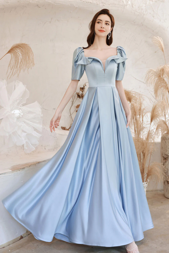 Woman wearing a light blue dress with ruffled sleeves against a neutral background