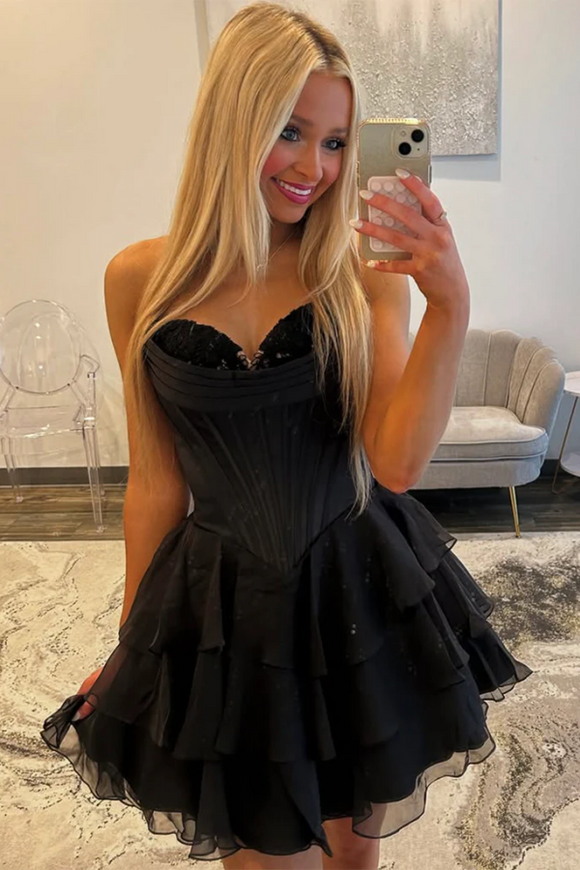 Woman taking a selfie wearing a black dress in an indoor setting.