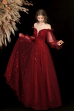 Woman wearing a red off-shoulder gown with sheer sleeves against a dark background