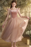 Woman in a pink dress standing in a garden with flowers and candles.