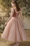 Woman in a pink dress standing outdoors with a rustic background