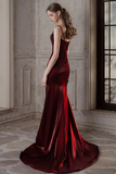 Woman in a burgundy evening gown standing in an elegant room with a large window.