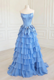 Blue strapless gown with layered skirt on a mannequin against a white wall.