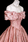 Pink evening gown with a large bow on a mannequin against a black background