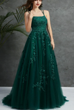 Woman wearing a green evening gown with floral embroidery against a gray background