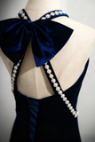 Navy blue dress with a large bow and pearl details on a mannequin.
