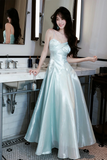 Woman in a light blue strapless gown standing in a bathroom.