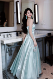 Woman in a light blue evening gown standing in a bathroom.