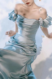 Woman wearing a light blue off-shoulder dress against a soft, blurred background